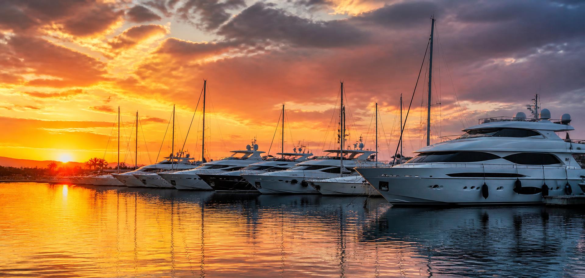 Yachts moored in a marina at sunset